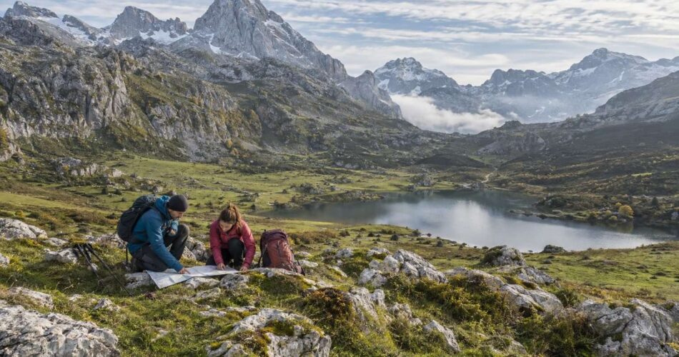 Senderistas preparando una ruta con mapa en un valle de montaña